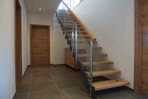 Bolzentreppe mit schwarzer Wange und Glasgeländer