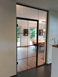 Raumhohe Glasanlage mit Drehtür und schwarzen Details