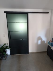 Ganzglas Schiebetürelement mit schwarzen Beschlägen